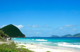 A catamaran sailing along the green hills of Tortola in the British Virgin Islands, the ultimate BVI yacht charter ground