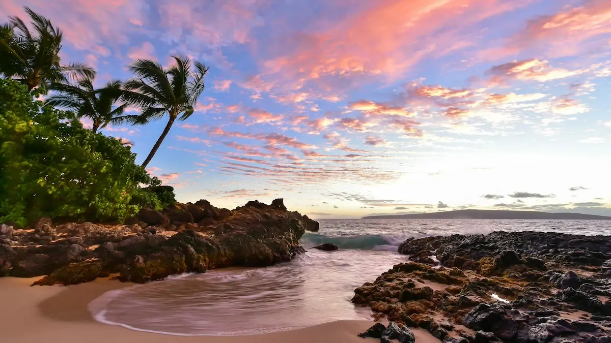 Intimate crescent of golden sand and black lava rock at Secret Beach in South Maui, a popular anchorage for a Maui yacht charter