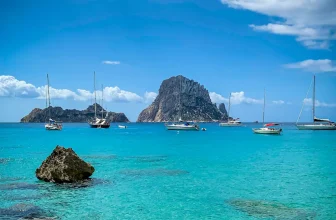 Turquoise bay with moored sailboats and Es Vedrà rock off Ibiza, Balearic Islands