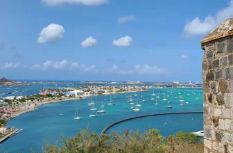 Historic stone fort overlooking Marigot Bay in St. Martin with turquoise water and anchored sailboats under a bright Caribbean sky.