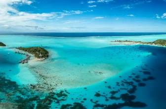 Aerial view of turquoise lagoon, motus and anchored boats at Bora‑Bora, French Polynesia